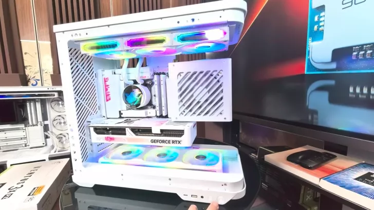 A white open-frame gaming PC case with RGB lighting houses an NVIDIA GeForce RTX graphics card, showcasing its internal components.