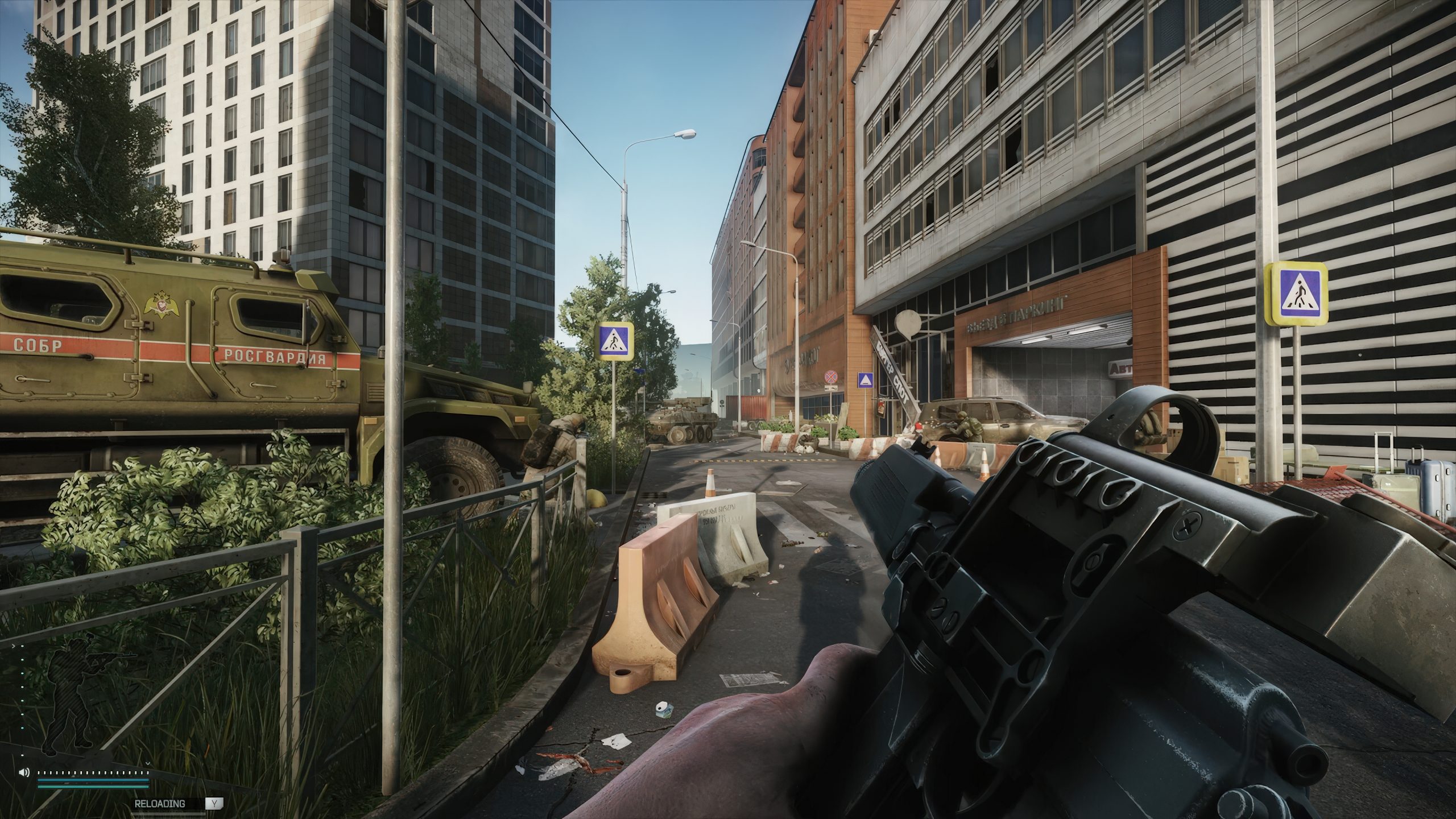 A first-person view in a video game shows a player holding a firearm on a deserted urban street with military vehicles and barricades, alongside buildings marked with Russian signage.