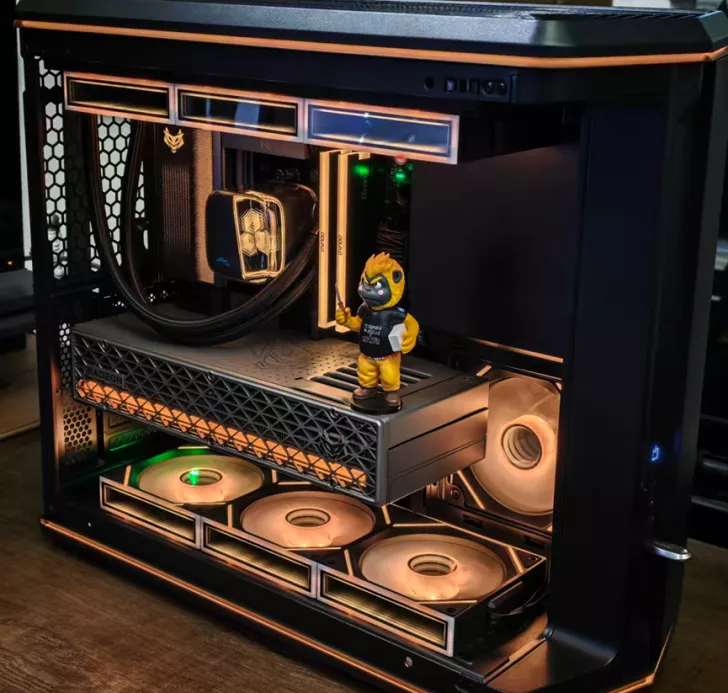 A PC build featuring an AMD Radeon graphics card, liquid cooling setup, and illuminated fans, with a small figurine standing on the GPU shroud.