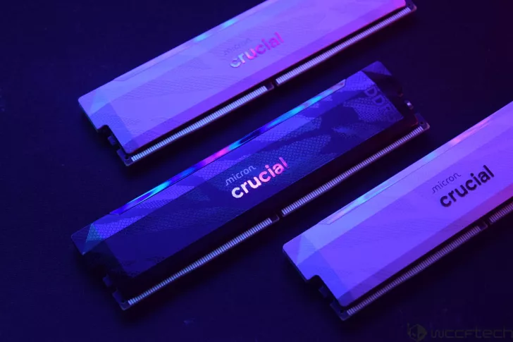 Three Micron Crucial DDR5 memory modules are illuminated under purple and blue lighting.